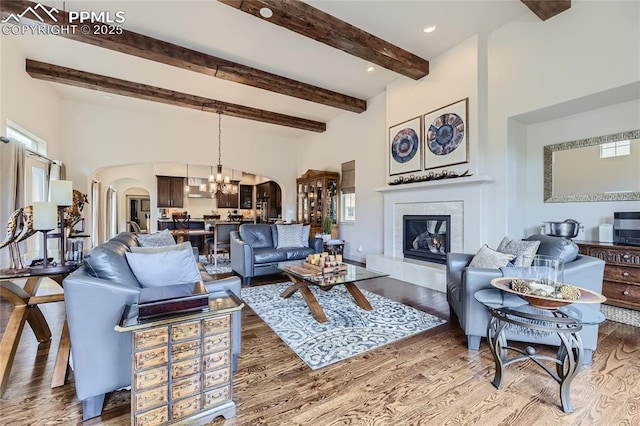 living room featuring hardwood / wood-style flooring, beamed ceiling, a healthy amount of sunlight, and a notable chandelier