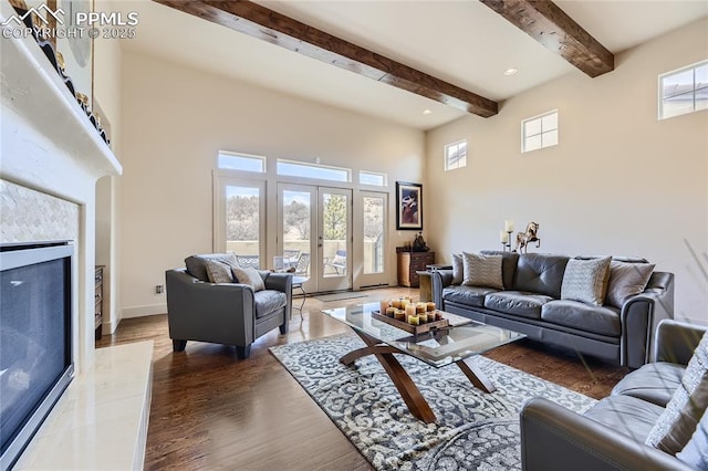 living room with a tile fireplace, a wealth of natural light, dark hardwood / wood-style flooring, and french doors