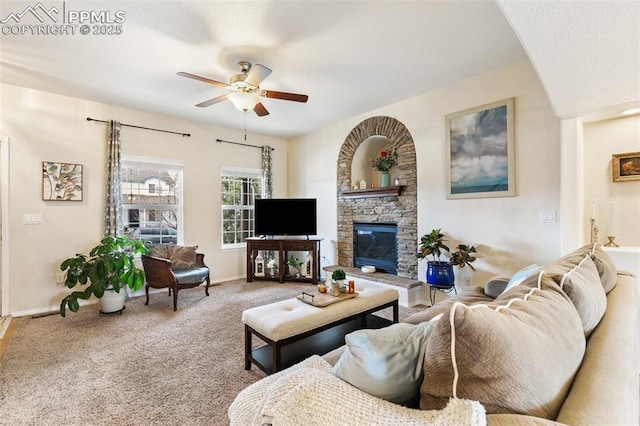 living room with carpet, a stone fireplace, and ceiling fan