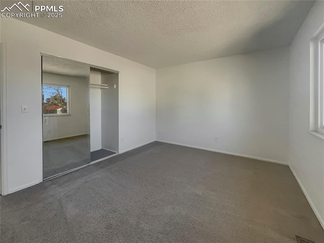 unfurnished bedroom with a closet, dark carpet, and a textured ceiling