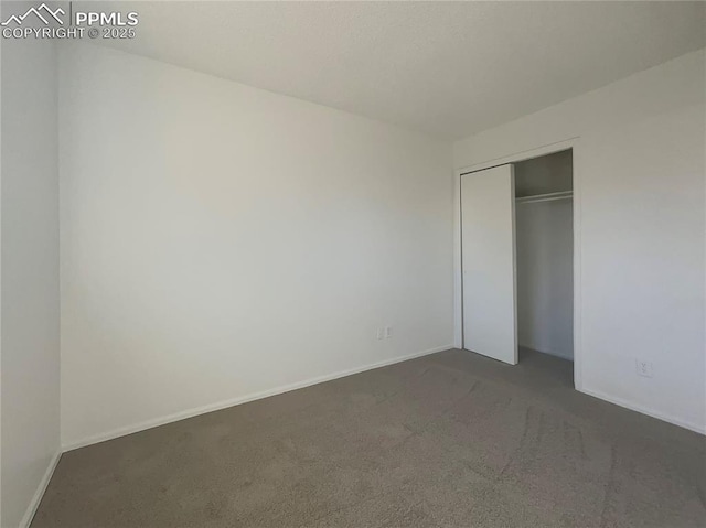 unfurnished bedroom with a closet and dark colored carpet