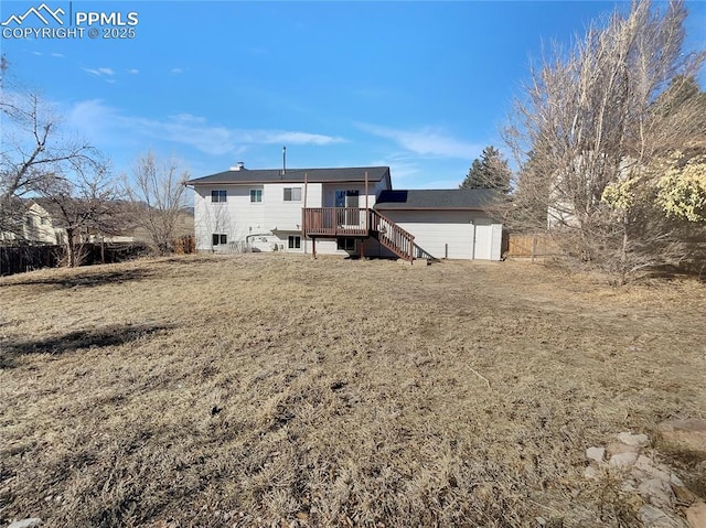 rear view of property featuring a wooden deck and a lawn