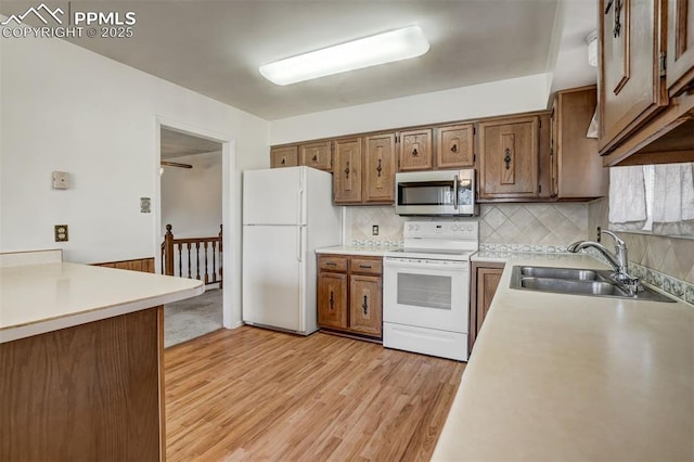 kitchen with white appliances, light hardwood / wood-style floors, sink, and decorative backsplash