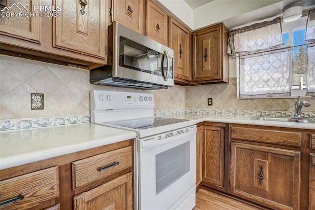 kitchen featuring backsplash, light hardwood / wood-style floors, sink, and white range with electric stovetop