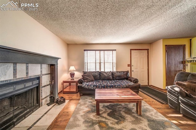 living room featuring light hardwood / wood-style floors, a tile fireplace, and a textured ceiling