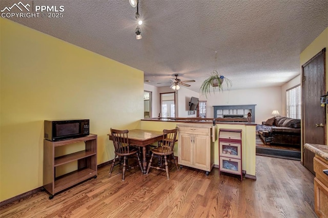 kitchen featuring ceiling fan, wood-type flooring, kitchen peninsula, and a textured ceiling