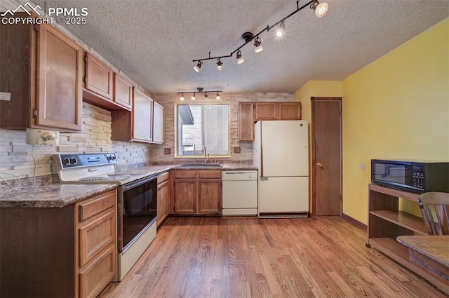 kitchen with sink, white appliances, backsplash, light hardwood / wood-style floors, and a textured ceiling