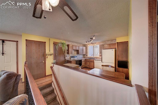 kitchen featuring sink, white appliances, a textured ceiling, ceiling fan, and light hardwood / wood-style floors