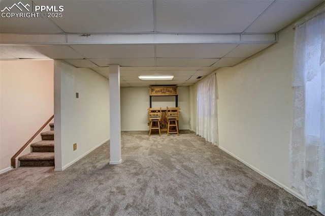 basement featuring bar, a paneled ceiling, and carpet