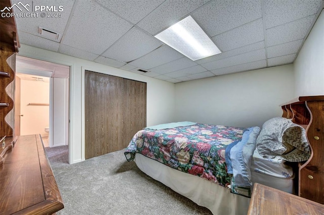 bedroom with a closet, carpet, and a drop ceiling