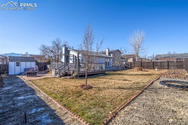 back of house with a shed, a yard, a patio, and a deck