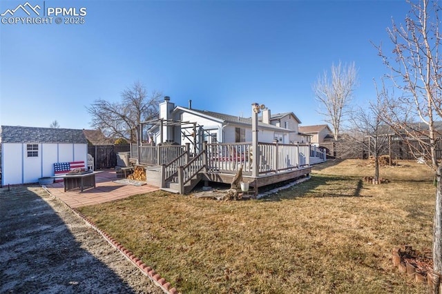 back of house with a lawn, a fire pit, a wooden deck, a shed, and a patio area