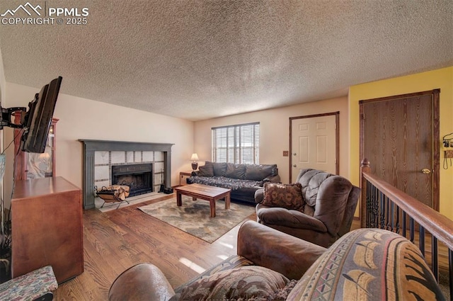 living room featuring a tile fireplace, a textured ceiling, and light wood-type flooring