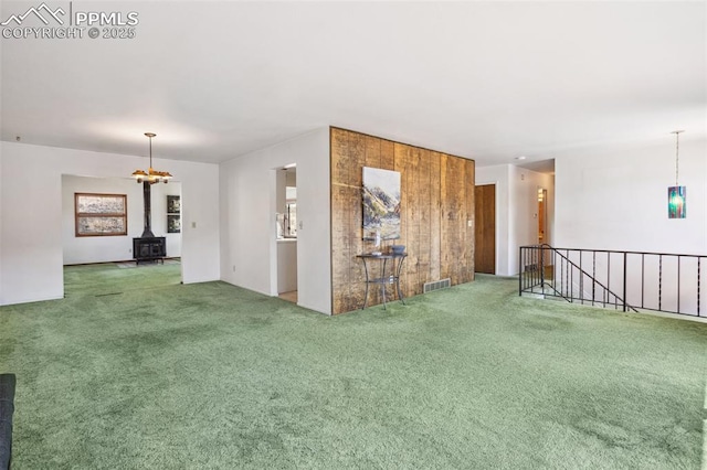 spare room with carpet flooring and a wood stove