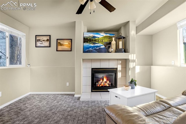 living room featuring dark carpet, a fireplace, and ceiling fan