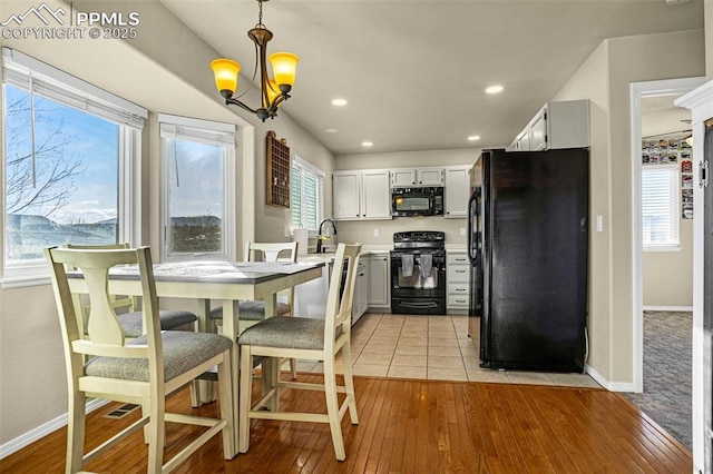 kitchen featuring hanging light fixtures, a notable chandelier, light wood-type flooring, and black appliances