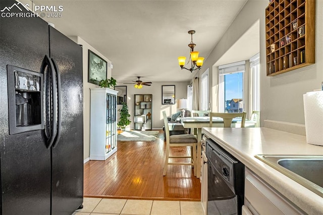 kitchen with ceiling fan with notable chandelier, decorative light fixtures, sink, light tile patterned floors, and black appliances