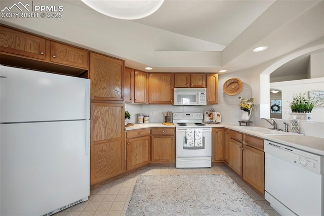 kitchen featuring lofted ceiling, sink, white appliances, and decorative backsplash