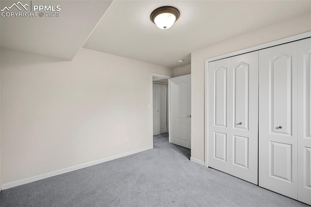 unfurnished bedroom with light colored carpet and a closet