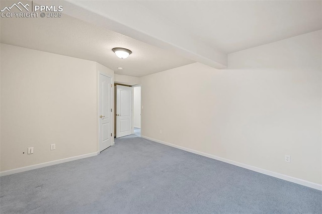 carpeted spare room featuring beamed ceiling