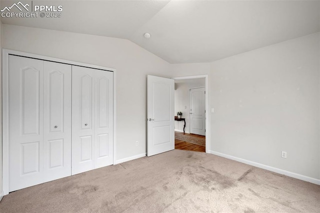 unfurnished bedroom featuring lofted ceiling, light colored carpet, and a closet