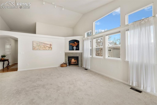 unfurnished living room featuring a fireplace, carpet floors, high vaulted ceiling, and rail lighting