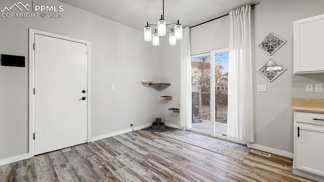 unfurnished dining area with a notable chandelier and light wood-type flooring