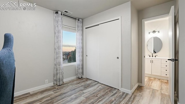 bedroom featuring sink, a closet, and light wood-type flooring