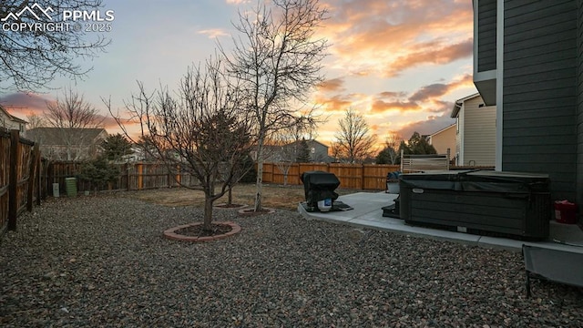 yard at dusk featuring a hot tub and a patio