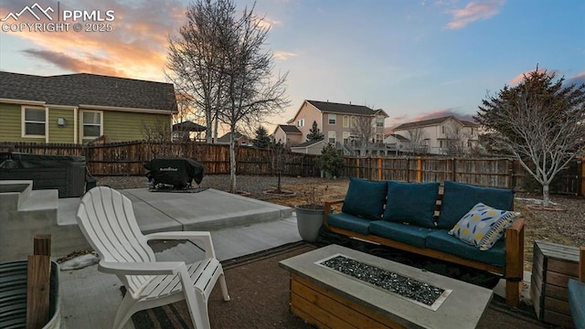 patio terrace at dusk with area for grilling, a hot tub, and an outdoor living space with a fire pit