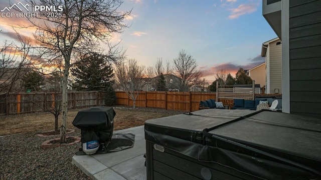 yard at dusk featuring a hot tub and a patio area