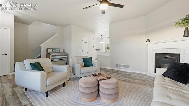 living room with ceiling fan with notable chandelier and light hardwood / wood-style flooring