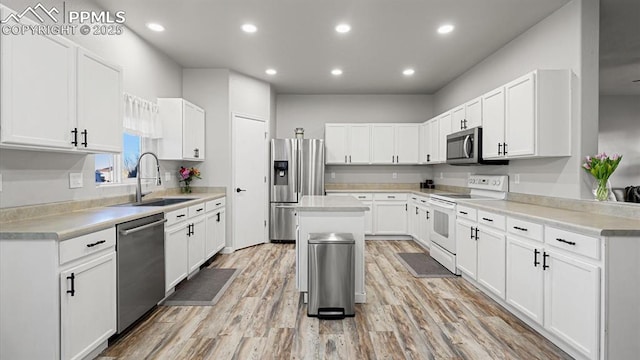 kitchen with white cabinetry, stainless steel appliances, sink, and a kitchen island