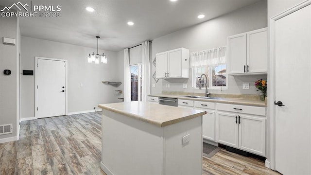 kitchen with sink, white cabinets, hanging light fixtures, a center island, and light hardwood / wood-style flooring