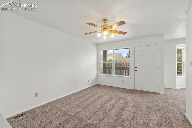 spare room with carpet floors, visible vents, baseboards, and ceiling fan