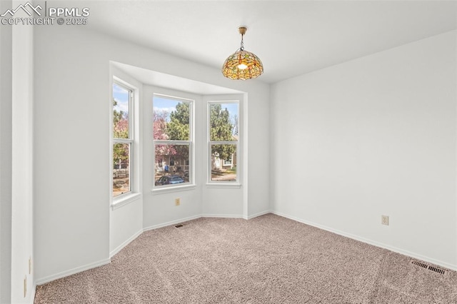 empty room with baseboards, visible vents, and carpet flooring
