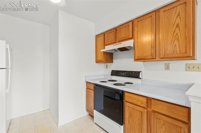 kitchen featuring under cabinet range hood, light floors, light countertops, freestanding refrigerator, and electric range oven