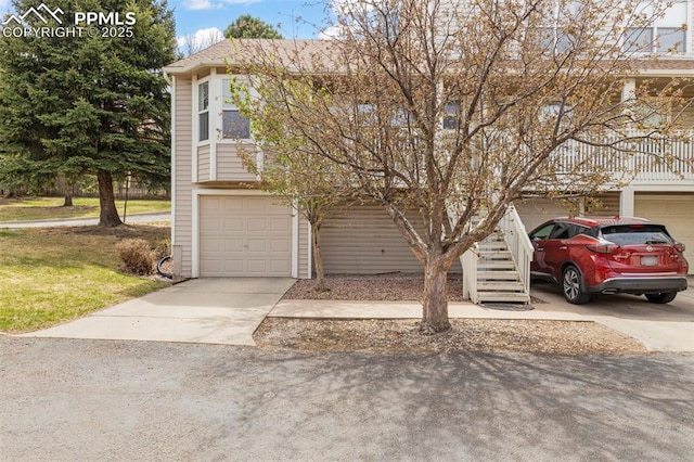 view of front facade with concrete driveway, an attached garage, and stairs