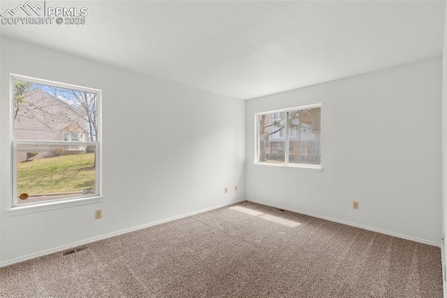 unfurnished room with carpet floors, visible vents, and baseboards