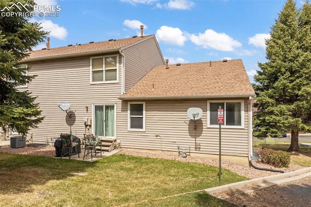 rear view of house featuring central air condition unit, entry steps, a patio area, a shingled roof, and a yard