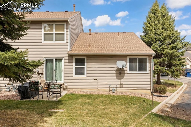 rear view of property featuring a lawn, roof with shingles, and a patio area