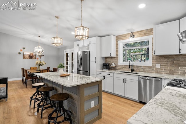 kitchen featuring sink, a kitchen island, appliances with stainless steel finishes, and white cabinets