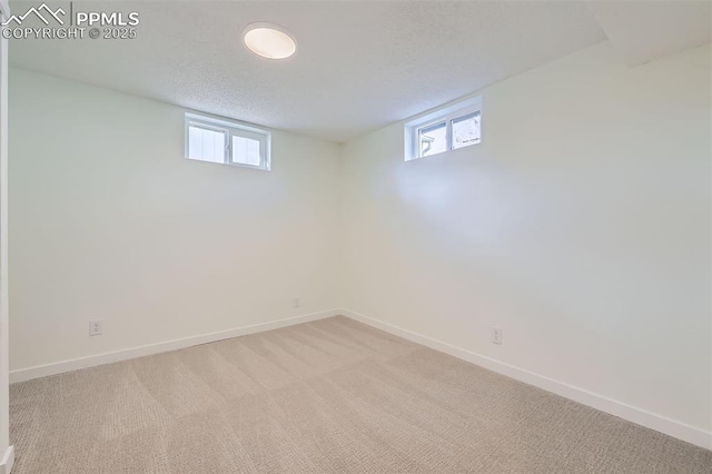 basement with light colored carpet, a textured ceiling, and a wealth of natural light