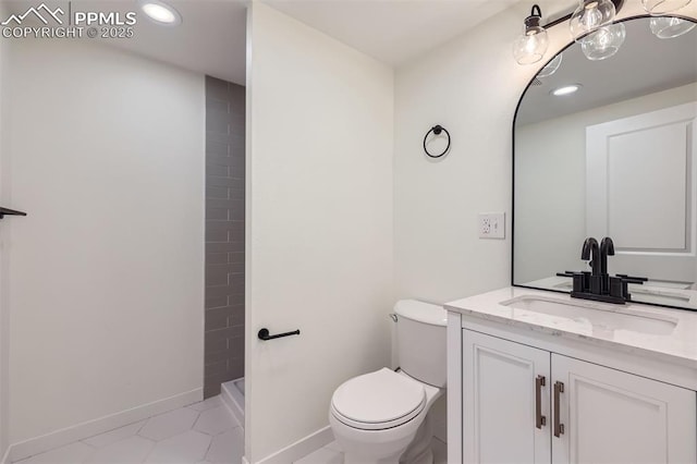 bathroom with tiled shower, vanity, and toilet