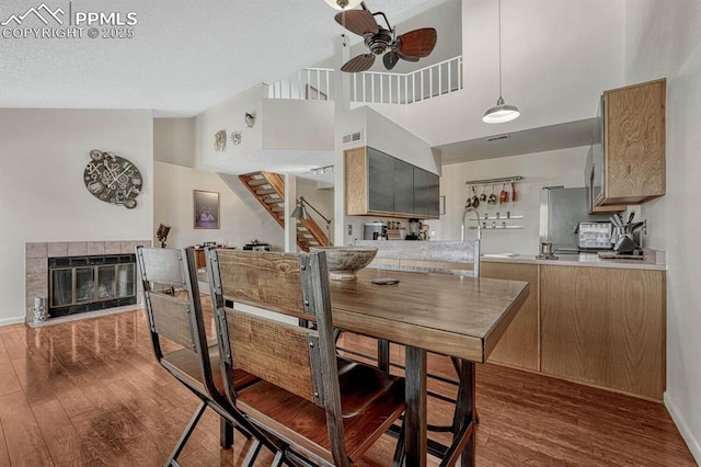 dining area with stairway, a fireplace, wood finished floors, and a ceiling fan