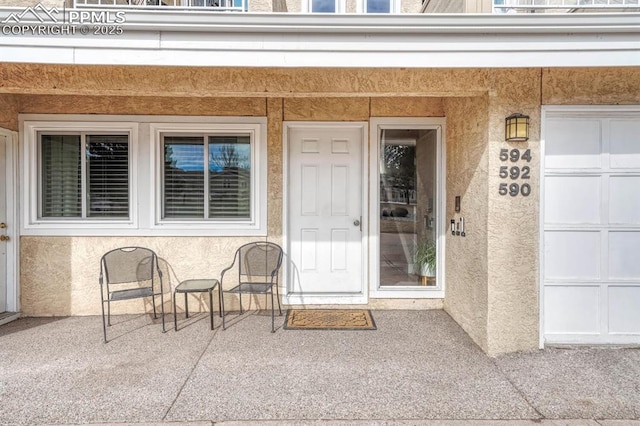 property entrance with a garage and stucco siding