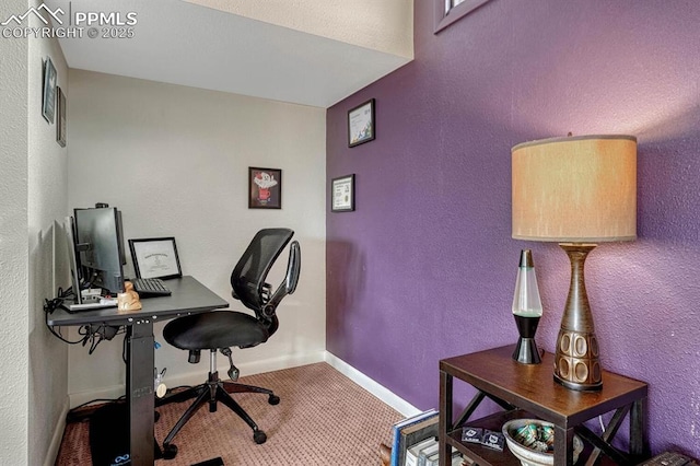 carpeted home office featuring baseboards and a textured wall