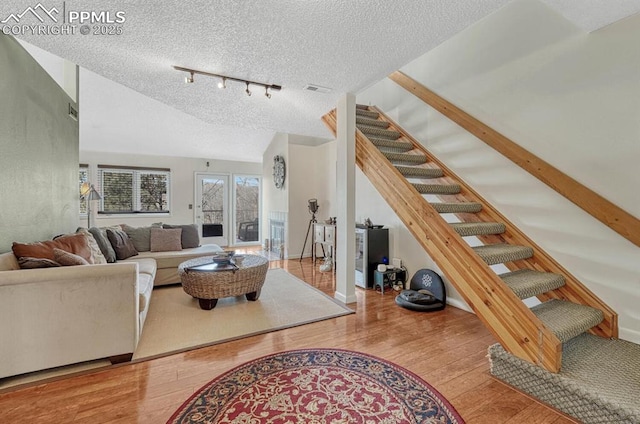 living area featuring baseboards, a textured ceiling, hardwood / wood-style floors, and stairs