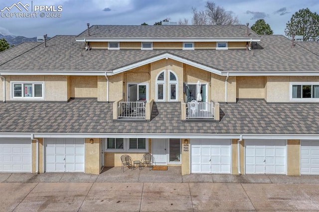 view of property with a garage, a balcony, and stucco siding