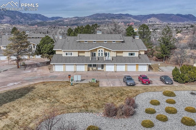 view of front facade featuring a garage, a shingled roof, a chimney, and a mountain view